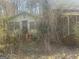 Needs TLC, this house with a brick chimney is surrounded by trees and shrubs at 405 W Richardson Rd, Oxford, GA 30054