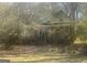 A fixer-upper home with a screened-in porch is nestled among trees, awaiting restoration at 405 W Richardson Rd, Oxford, GA 30054