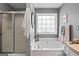 Bright bathroom with tub, frosted glass shower doors and natural light at 1022 Miss Amber Way, Locust Grove, GA 30248