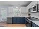 Updated kitchen with stainless steel appliances, white backsplash and blue and white cabinets at 1022 Miss Amber Way, Locust Grove, GA 30248