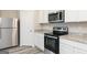 Modern kitchen features stainless steel appliances, granite countertops, white cabinetry, and wood grain flooring at 301 Limestone Circle, Conyers, GA 30013