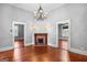 Open living room featuring a fireplace, hardwood floors, chandelier, and natural light from other rooms at 85 Bryan St, Mcdonough, GA 30253