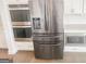 Kitchen with stainless steel refrigerator, built-in ovens, and white cabinets, offering ample storage and style at 3695 Andover St, Cumming, GA 30028