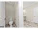 Modern half bathroom featuring a toilet and access to the vanity area with elegant tiling and gold fixtures at 1188 Oakland Sw Ln, Atlanta, GA 30310