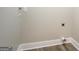 A laundry hookup featuring modern wood floors, base trim and neutral walls with electrical and drain access at 5122 Hillcrest Nw Dr, Covington, GA 30014