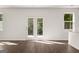 Living room with hardwood floors, white walls, and light from windows and French doors at 596 Whitman Lane # 2025, Stockbridge, GA 30281