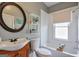 Cozy bathroom featuring a round mirror, wooden vanity, and a shower-tub combination at 988 Allene Sw Ave, Atlanta, GA 30310