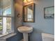 Powder room featuring a pedestal sink, framed mirror, and natural light at 509 Cowpens Rd, Social Circle, GA 30025