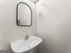 Clean, white bathroom with a pedestal sink, simple mirror, and fresh aesthetic at 949 Pike Forest Dr, Lawrenceville, GA 30045