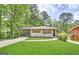 Charming brick home with a lush green lawn, a carport, and mature trees providing shade at 2676 Stone Rd, East Point, GA 30344