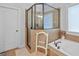 Shower and tub area featuring tiled walls, glass shower enclosure, neutral accents, and a comfortable chair at 100 Chantilly Ln, Fayetteville, GA 30215