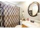 Bathroom with patterned shower curtain, round mirror, and single sink vanity at 1103 Larkspur Dr, Locust Grove, GA 30248