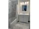 Well-lit bathroom with gray marbled tile, shower-tub combo and vanity with white cabinets at 813 Creekgarden Court, Atlanta, GA 30339