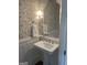 Chic powder room featuring patterned wallpaper, pedestal sink, and a stylish mirror, creating a sophisticated space at 813 Creekgarden Court, Atlanta, GA 30339