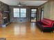 Sunlit living room with hardwood floors, brick fireplace, and a black and red sofa at 6099 Winview Dr, Forest Park, GA 30297