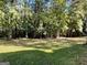 View of the flat backyard featuring healthy green grass and mature trees at 6332 Valley Dale Dr, Riverdale, GA 30274