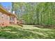Expansive backyard showcasing lush lawn and mature trees with a brick home and stairs to the back porch at 315 Antebellum Way, Fayetteville, GA 30215
