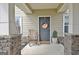 Covered front porch featuring stone columns, a rocking chair, and seasonal decor at 676 Mcbride Rd, Fayetteville, GA 30215
