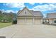 Detached three-car garage showcasing neutral doors and a spacious concrete driveway, complemented by lush greenery at 676 Mcbride Rd, Fayetteville, GA 30215