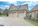Detached three-car garage showing doors and a concrete driveway, accented by mature landscaping and natural light at 676 Mcbride Rd, Fayetteville, GA 30215