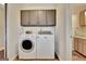 Well-lit laundry area featuring gray cabinets, modern washer and dryer, and neutral tile flooring at 676 Mcbride Rd, Fayetteville, GA 30215