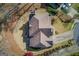 Aerial view shows house with a neutral roof, landscaping, driveway and surrounding woods at 5808 Deer Crossing Dr, Sugar Hill, GA 30518