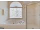 Bright bathroom features a soaking tub under an arched window, and a separate glass enclosed shower at 5808 Deer Crossing Dr, Sugar Hill, GA 30518