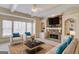 Comfortable living room with a stone fireplace, built-in bookshelves, and large windows at 5808 Deer Crossing Dr, Sugar Hill, GA 30518
