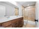 Bathroom featuring double sinks, warm wood cabinetry, neutral wall tile, and a glass-enclosed shower at 1619 Tide Mill Rd, Cumming, GA 30040