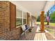 Inviting front porch with wooden flooring, brick columns, and comfortable seating with an American flag at 2079 Leguin Mill Rd, Locust Grove, GA 30248