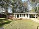 Charming single-story home featuring a brick facade, covered porch, and attached carport nestled among mature trees at 2087 John Wesley Ct, Decatur, GA 30035