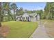 Exterior view of home with long driveway leading to the side-entry garage, lush lawn, and mature trees at 2112 Highway 54, Moreland, GA 30259