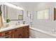Bright bathroom features a wooden vanity with a large mirror and a soaking tub by the window at 313 Dingler Rd, Moreland, GA 30259