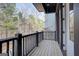 View of a wood deck balcony with black railings and trees in the background, providing a peaceful outdoor space at 434 Selborne Way, Chattahoochee Hills, GA 30268