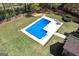 Aerial view of a sparkling swimming pool in a lush backyard surrounded by green grass and trees at 249 Edenwylde Ct, Hampton, GA 30228