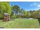 Expansive backyard featuring a sparkling in-ground pool, a playhouse, and lush green lawn surrounded by mature trees at 249 Edenwylde Ct, Hampton, GA 30228