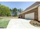 Brick home featuring a spacious driveway leading to a two-car garage, surrounded by lush greenery and trees at 249 Edenwylde Ct, Hampton, GA 30228
