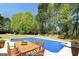 Backyard swimming pool with a wood table and chairs on the pool deck for outdoor dining at 249 Edenwylde Ct, Hampton, GA 30228