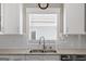 Well-lit kitchen with stainless steel sink, granite counters, and white cabinets at 5124 N Pratt St, Covington, GA 30014