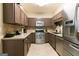 Galley kitchen features stainless steel appliances, gas range, and tile floors at 702 Las Brasis Ct, Peachtree City, GA 30269