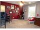 Bedroom featuring neutral carpet, a red accent wall, a ceiling fan, and plentiful natural light from a large window at 500 Hayfield Ct, Locust Grove, GA 30248