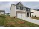 Two-story home with a two-car garage, a mix of siding and brick, and a young tree in the front yard at 161 Aster Ave, Locust Grove, GA 30248