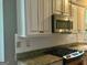 Kitchen featuring stainless steel microwave above a matching oven, granite countertop, and ample cabinet space at 9340 Basswood Way, Jonesboro, GA 30236