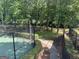 Green tennis court featuring a fence and a walkway in a wooded area at 9340 Basswood Way, Jonesboro, GA 30236