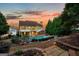 Gorgeous backyard featuring a pool, outdoor bar area, and lush landscaping at dusk at 119 Brookgrove Ln, Peachtree City, GA 30269
