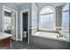 Bathroom showcasing a soaking tub, tiled walls, and an arched window for natural light at 119 Brookgrove Ln, Peachtree City, GA 30269