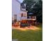 Backyard features an elevated deck with seating, beautiful landscaping, and tasteful lighting for evening enjoyment at 735 River Ridge Ln, Suwanee, GA 30024
