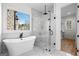 Bright bathroom features a soaking tub, glass enclosed shower, marble tile, and a large window at 5265 Brookhollow Dr, Douglasville, GA 30135