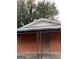 Close up of a boarded up red brick home with rusted awning and overgrown bushes at 1827 Thomasville Se Dr, Atlanta, GA 30315