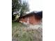 Side view of a boarded up red brick home with an awning and overgrown lawn at 1827 Thomasville Se Dr, Atlanta, GA 30315